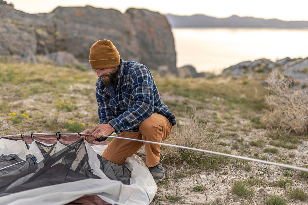 A man thoroughly enjoying his camping trip, while comfortably dressed in his Whiskey Denim Adventure Fit - 6th Gen jeans.