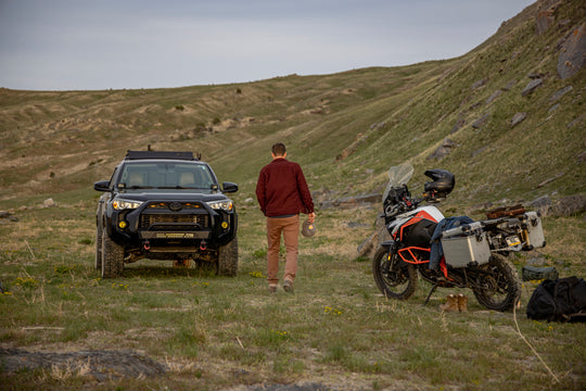Man with off-road car and motorcycle, savoring the outdoor scenery in his Tobacco Brown Adventure Fit - 6th Gen Bulletprufe Jeans.