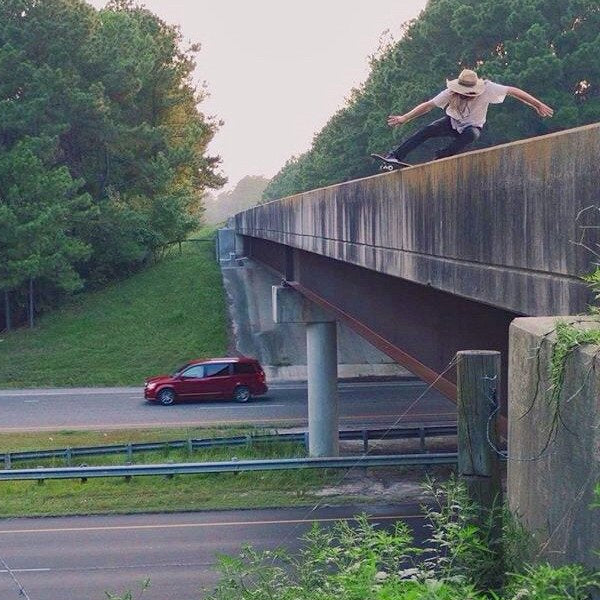 A man leaps off a bridge in stylish Blackout Denim Slim Fit 6th Gen Bulletprufe Jeans, designed with a slim (not skinny) fit that strikes the ideal balance between durability, comfort, and versatility.