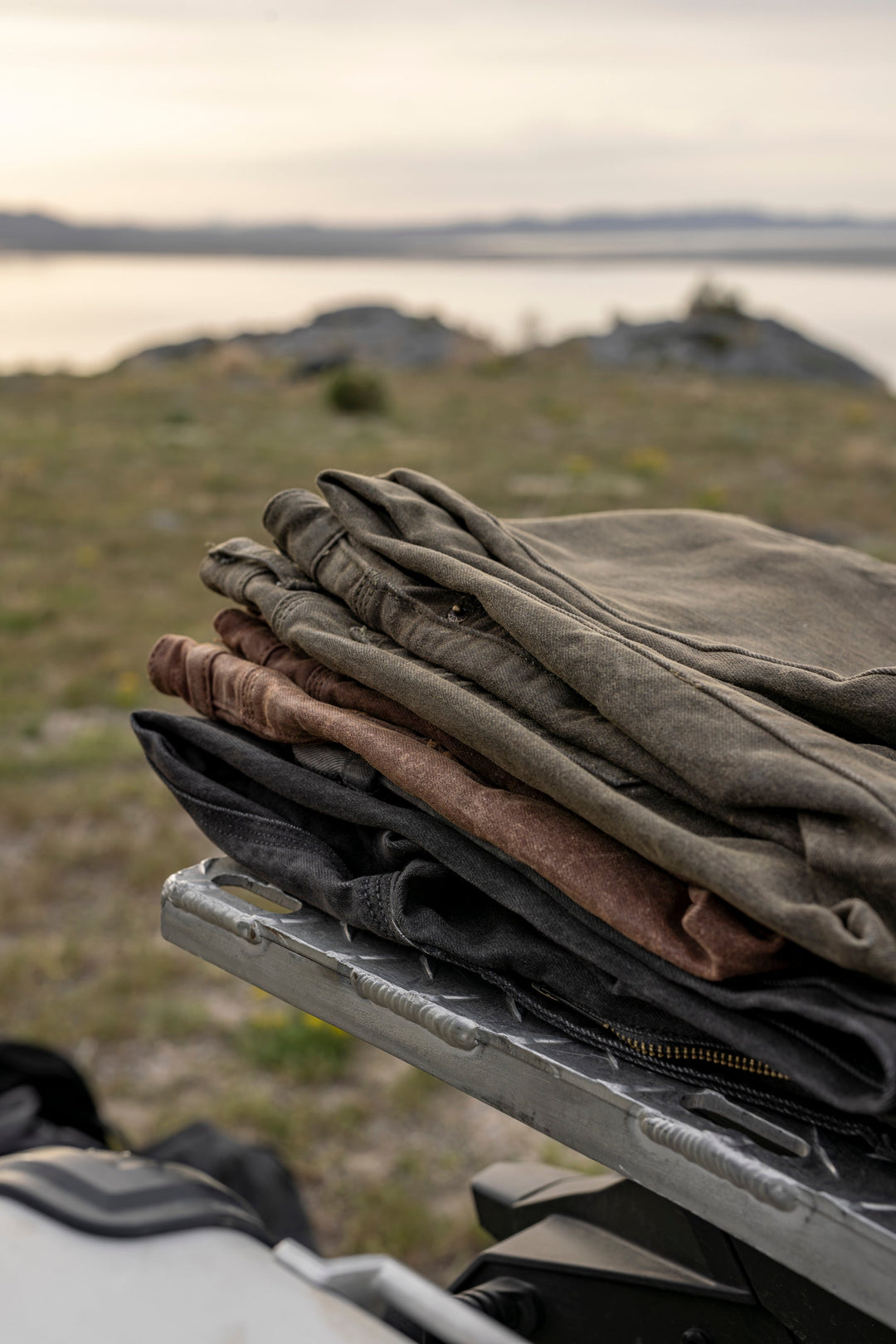 A collection of Bulletprufe Custom Waxed Tin-Cloth laid out in an outdoor adventure setting.