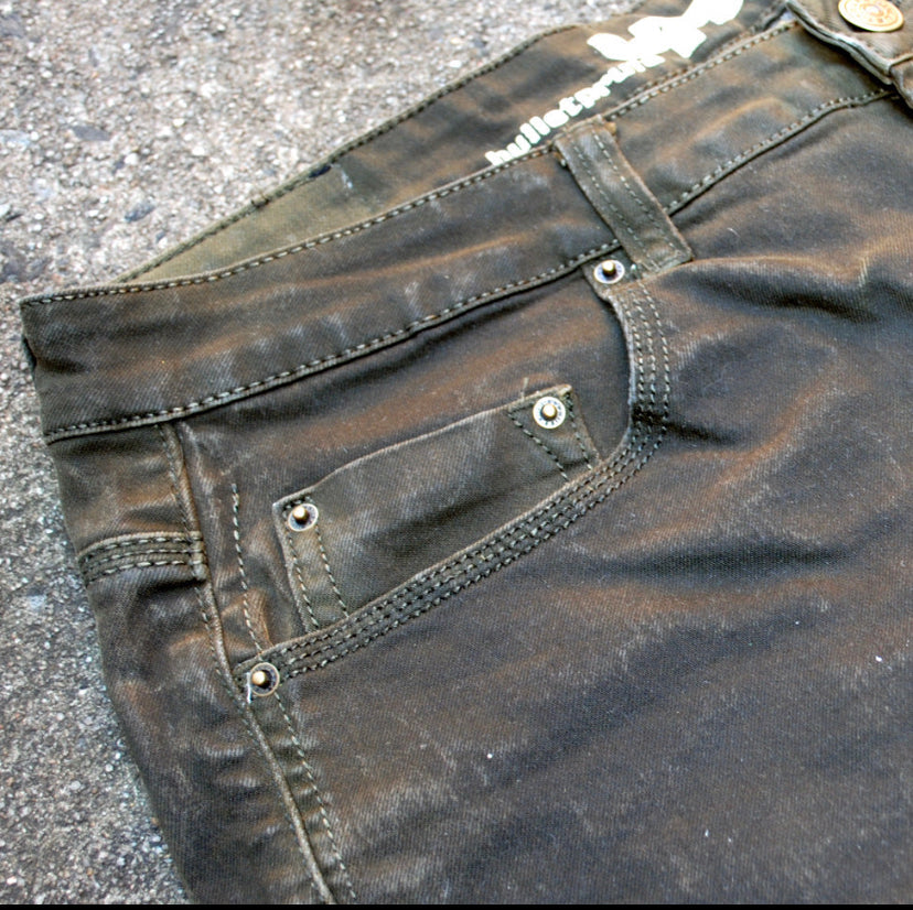 Slate Grey Slim Fit Bulletprufe Jeans close up view of pocket against a sandy backdrop.