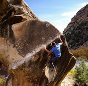 A man in Midnight Blue Denim - Adventure Fit - 4th Gen, conquering a rock as part of his adventurous journey.